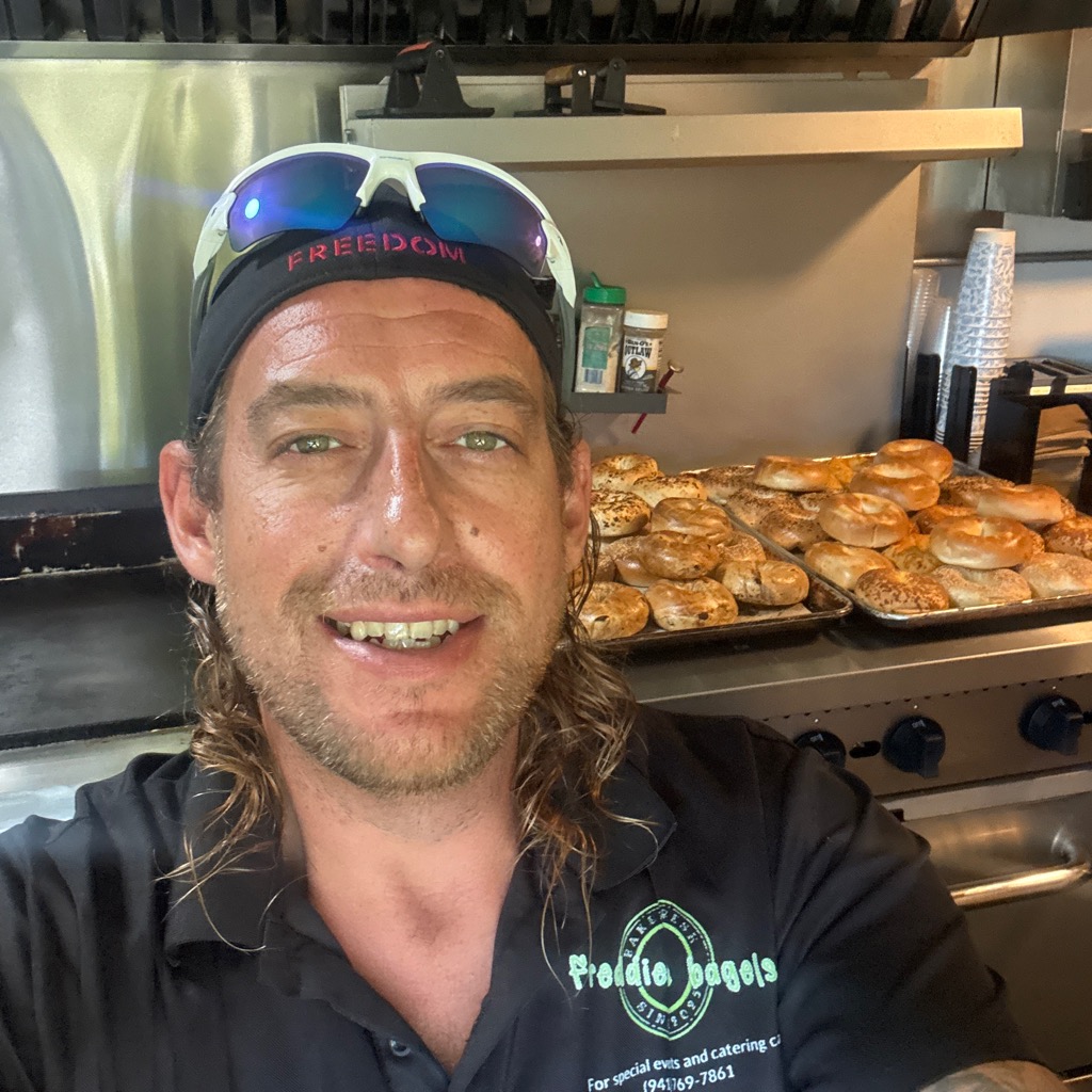 Freddie inside the truck with fresh trays of bagels behind him